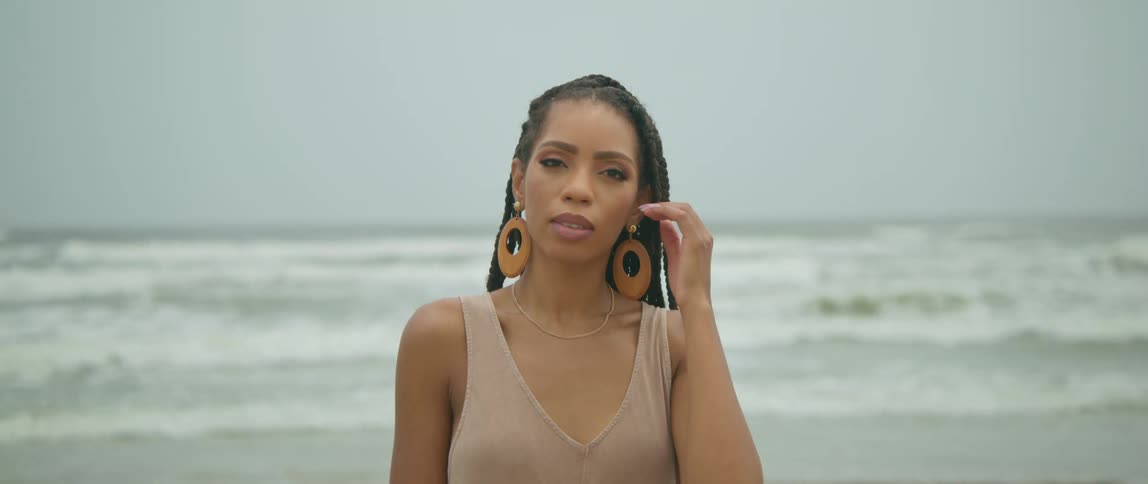 A woman stands on the shore as waves roll in