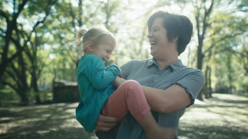 A woman laughs as she holds her child