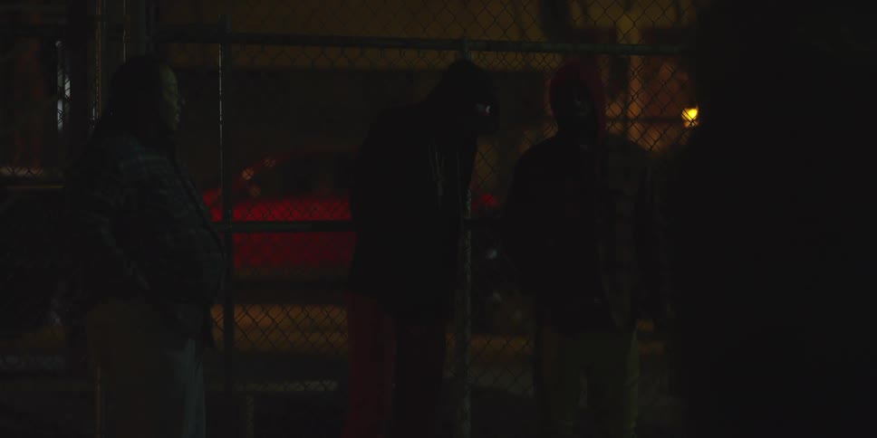 People are standing near a fence at night