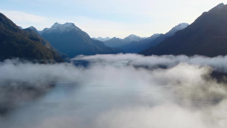 Dense fog fills in the valleys in between tall mountains