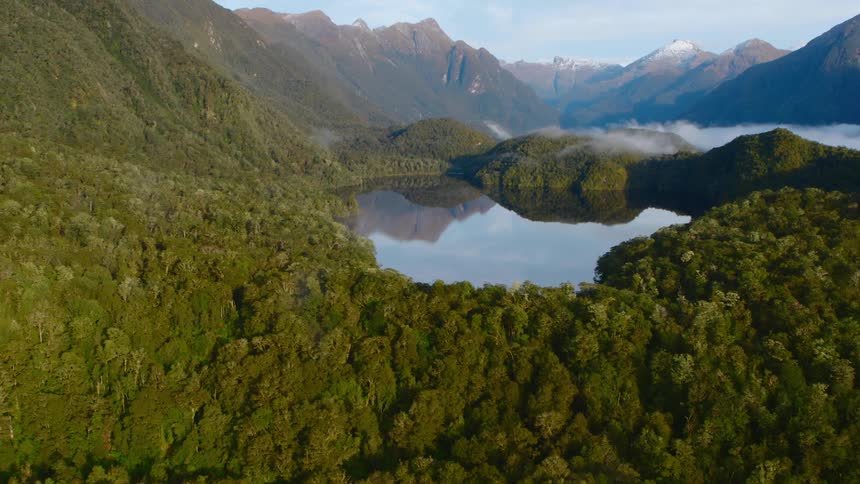 Lake surrounded by forests and a mountain range in the distance