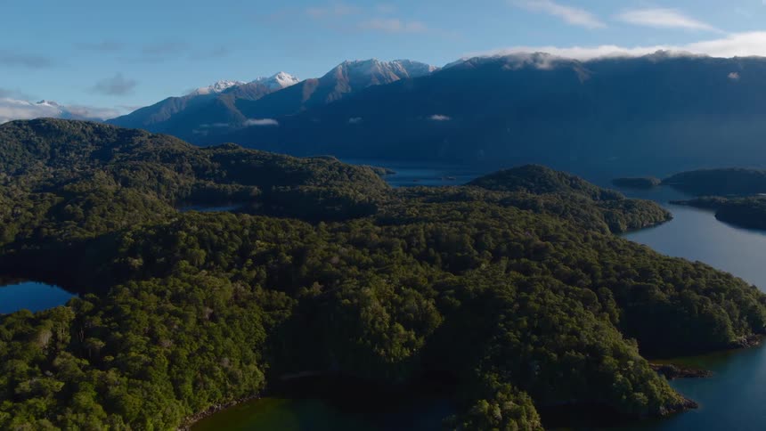 A lake with land with a mountain range the sky and clouds in the background