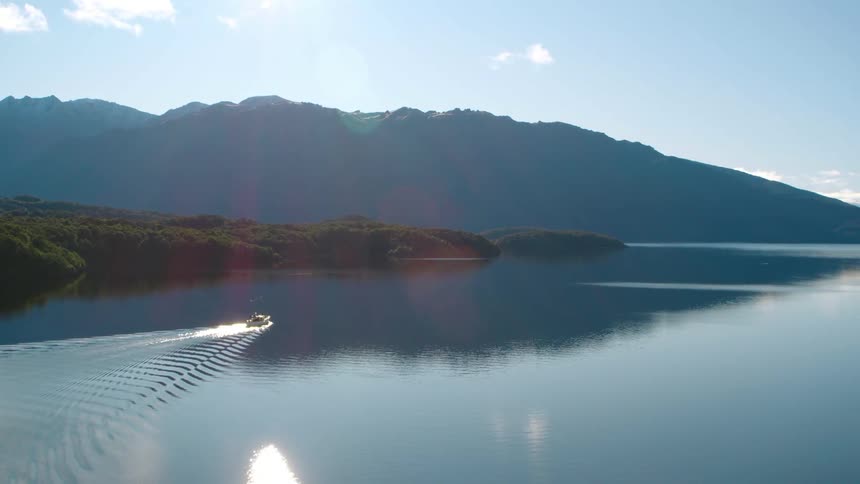 A boat driving on a quiet lake surrounded by hills