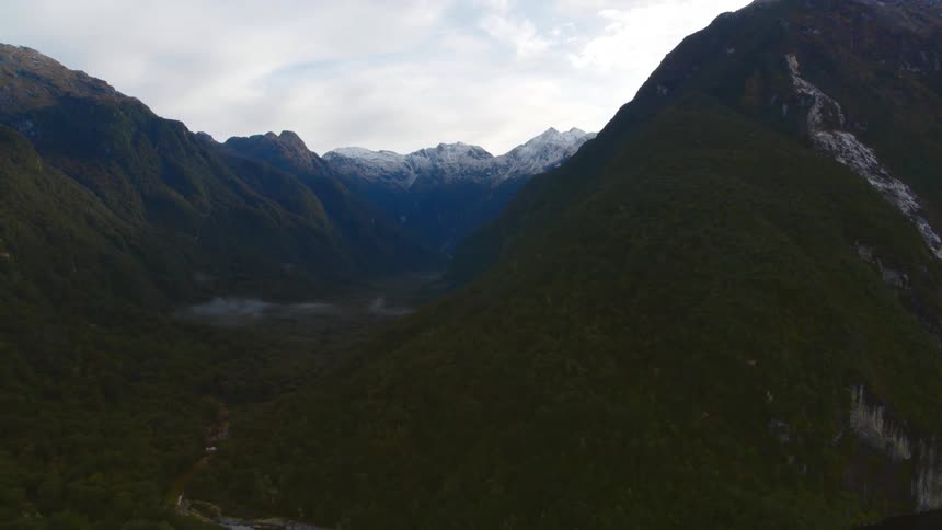 Aerial view of high mountains and valley against the cloudy sky