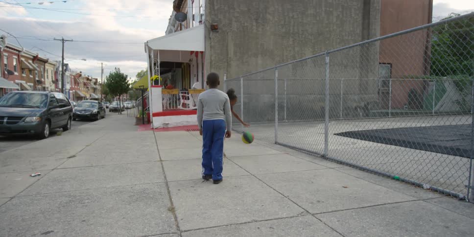 A boy follows another boy dribbling a basketball