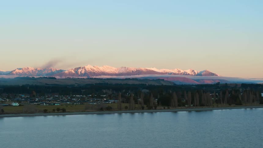 Lake and coastal community with mountains in the distance under a clear sky