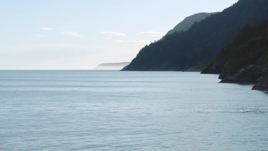A coast with land and sea with the sky and clouds in the background