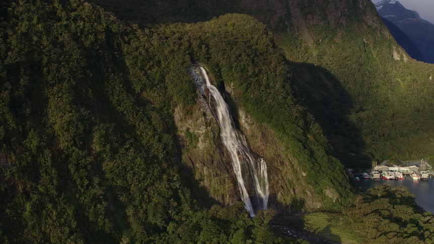 Aerial view of a waterfall on the side of a mountain near a lake