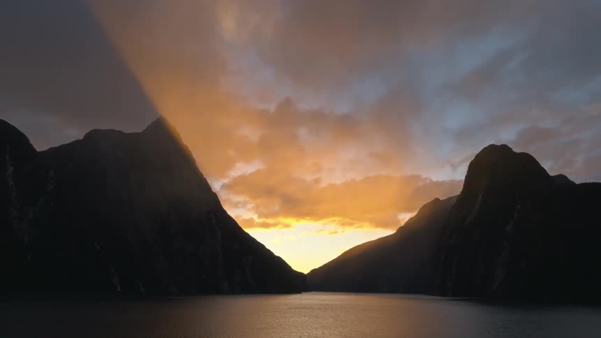 Lake surrounded my mountains and the sun setting between two mountains