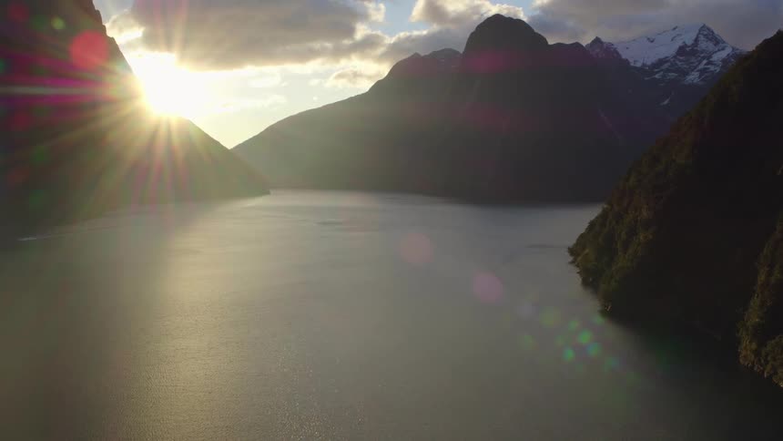 Lake with the sun setting between mountains in the distance