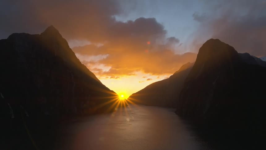 Lake surrounded by mountains and the sun is rising between two mountains