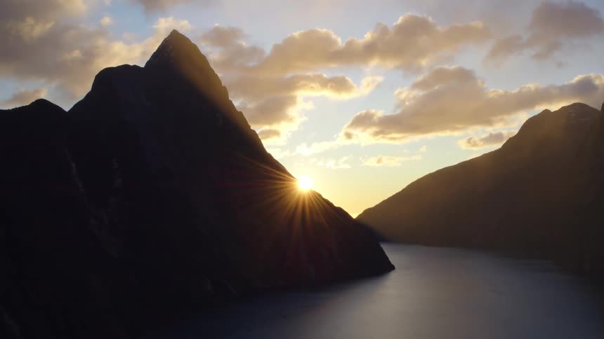 Lake between mountains under a cloudy sky as the sun is setting