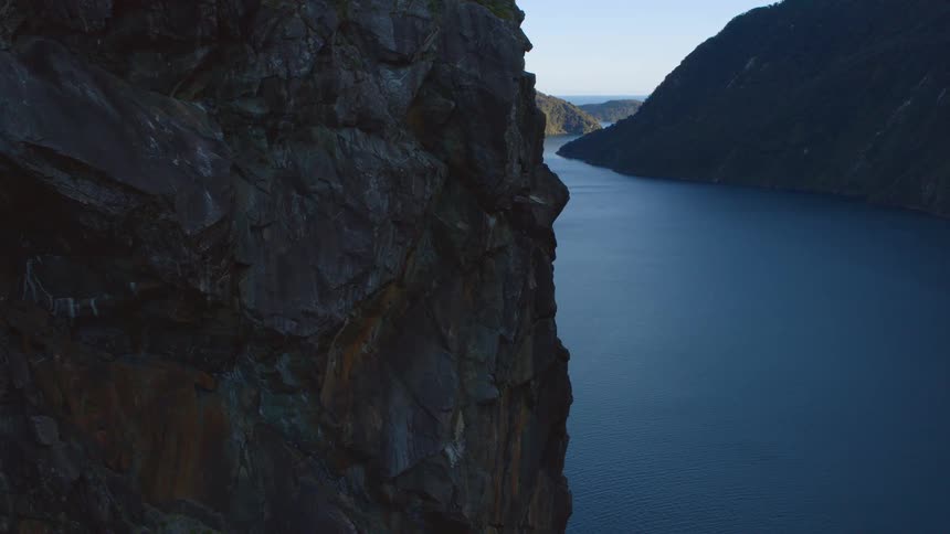 A river runs between two tall mountains towards the ocean