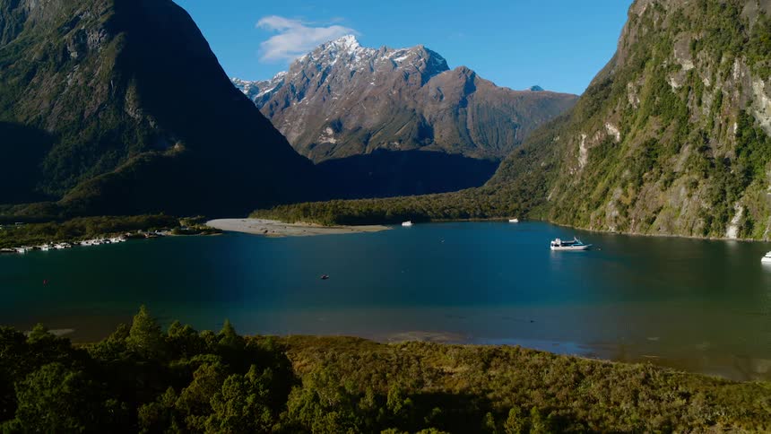 An aerial view of a boat floating on a lake surrounded by tall mountains