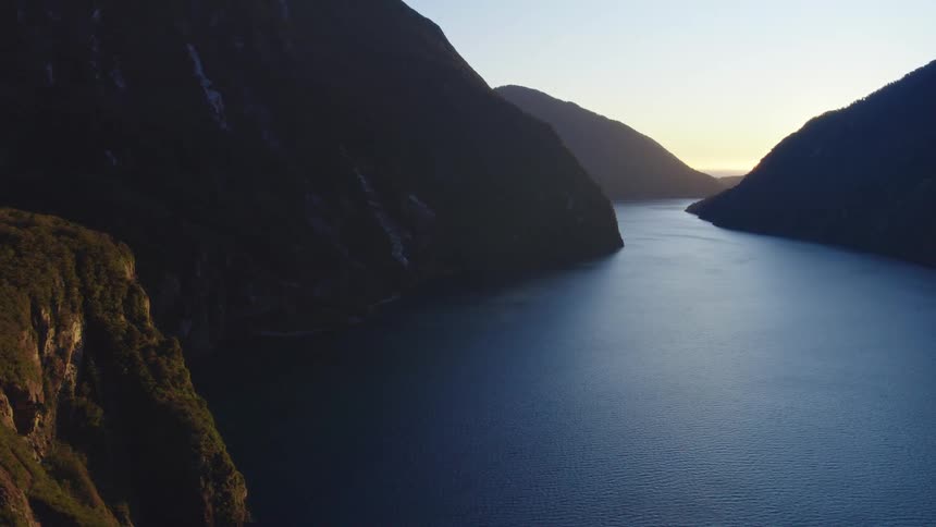 Calm river between mountains being silhouetted against the sunset