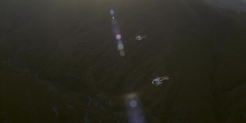 Pair of helicopters flying across the canyon in slow motion