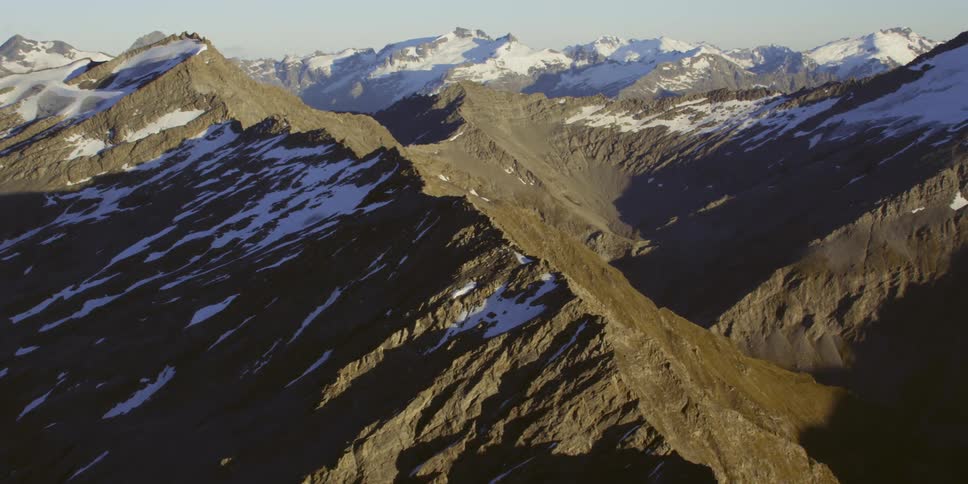 Sun casts shadows over snow dotted mountain range
