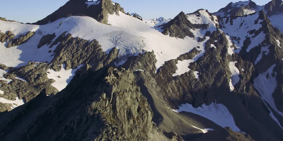 Aerial view of snow covered peaks in mountain range