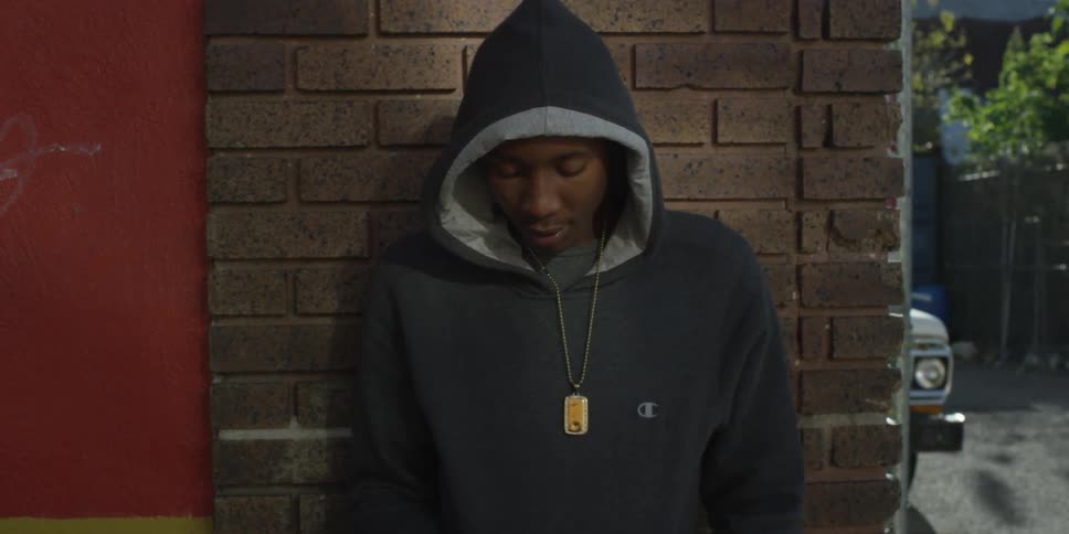 A man in a black hoodie looks around