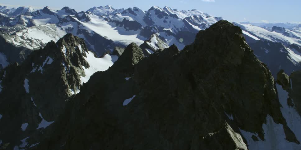 Jagged rocky mountain peaks with sun shining on the snow