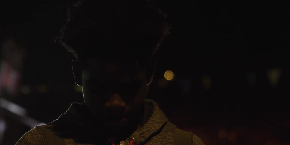 A man looks down then up at night