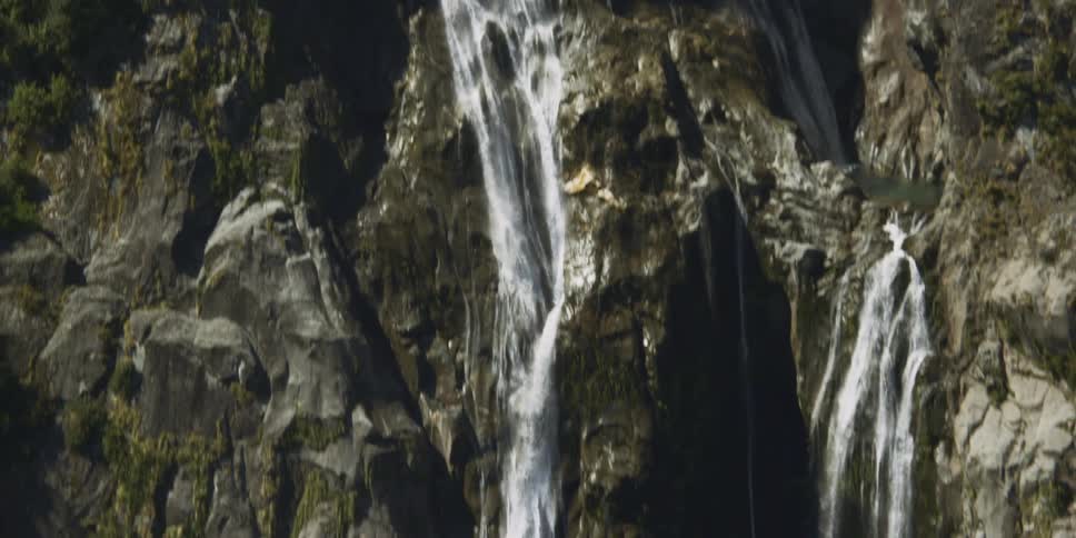 Water cascades down the side of a mountain into a stream below