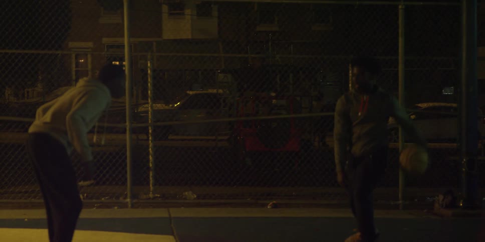 Two people are playing basketball at night