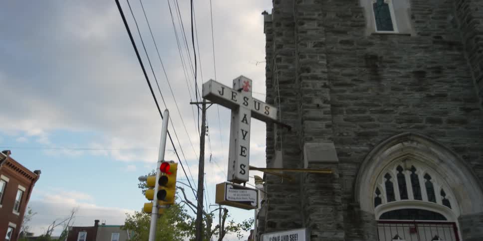 A sign that says 'jesus saves' hangs from an old building