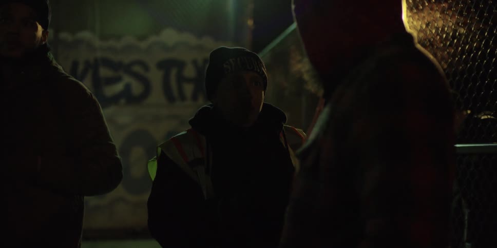 A man speaking with a security guard at night