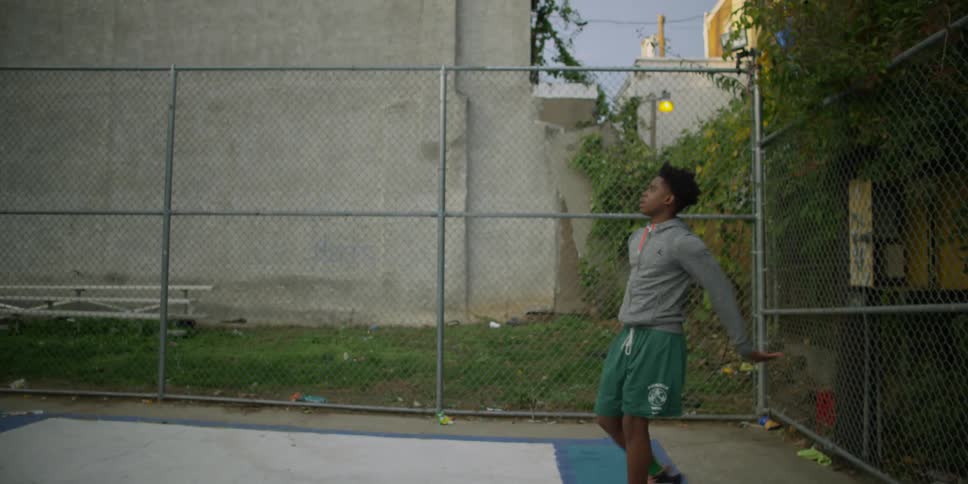 A boy in green shorts shoots a basket