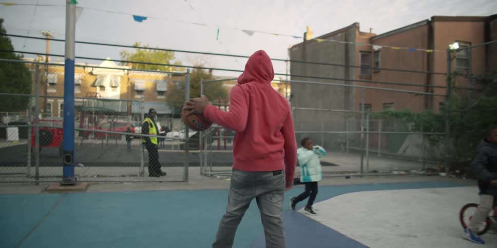 People are playing in a park riding bikes and playing basketball