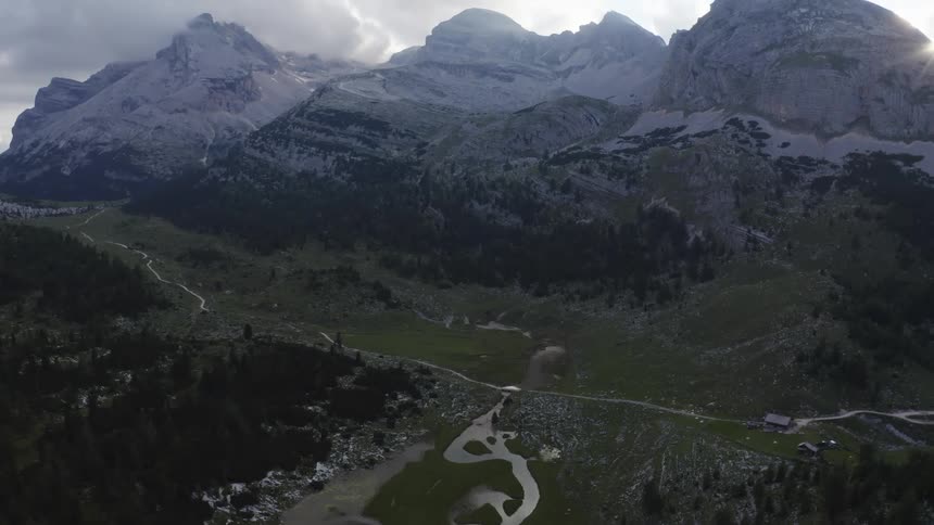 A neighborhood sits near a river in a field below a mountain range