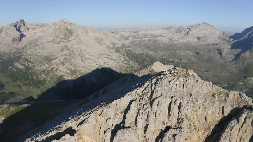 High atop a towering and rocky mountain is a lone cross standing tall