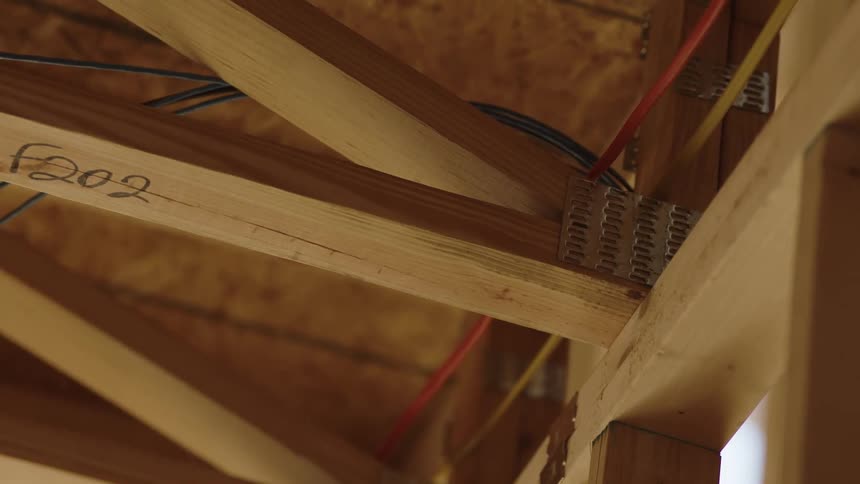 Cables and wires wrap around wood beams in a building under construction