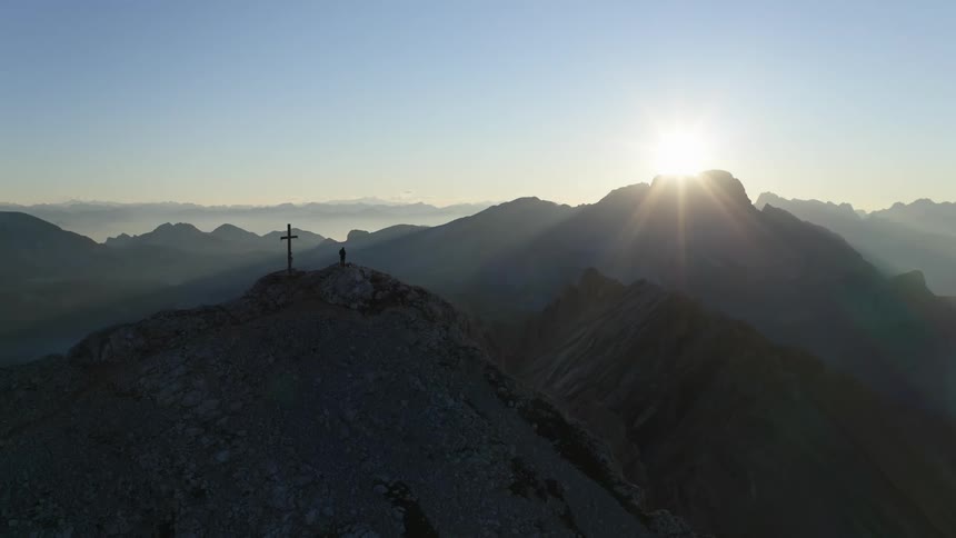 The sun is rising and creating a silhouette of a mountain top