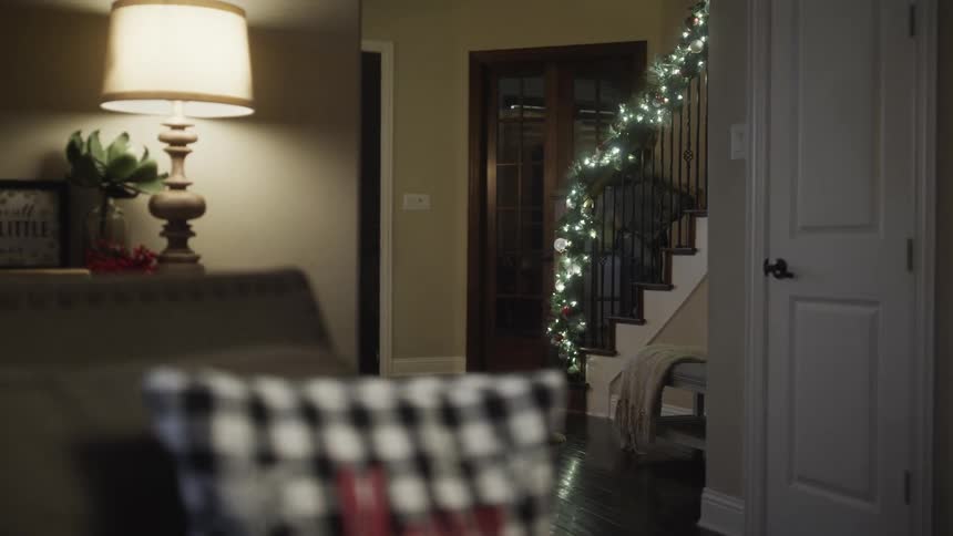 Father carries daughter upstairs in his arms in christmas decorated house