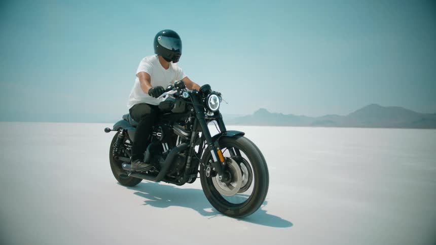 A man is racing a motorcycle across a salt flat