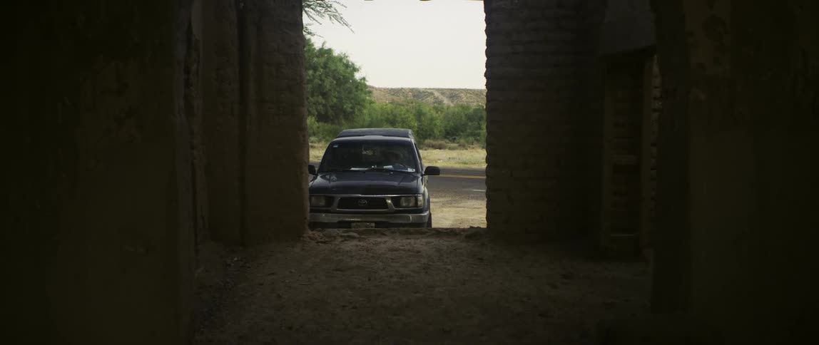 Man with brown hat short sleeve shirt and parks dark pickup truck at the side of road and gets out of the vehicle