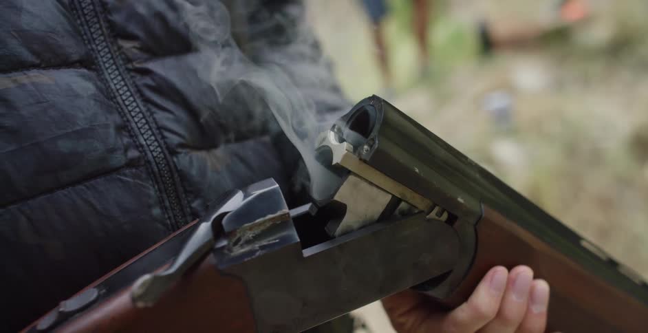 A man pulling a smoking shell from a shotgun