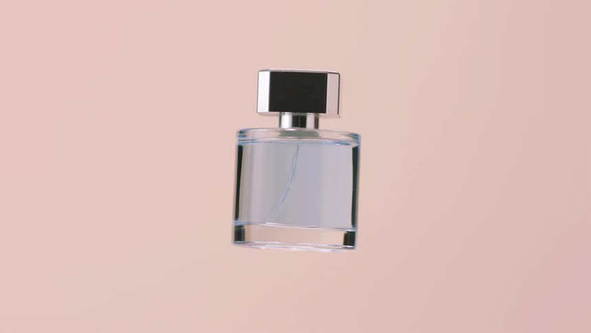A bottle of perfume rotating in a pink room