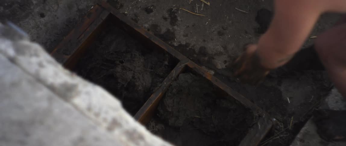 A woman is setting something down into a large hole