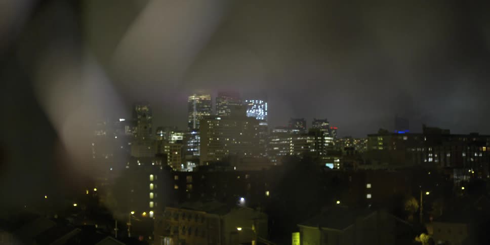 View through a fence of a city skyline at night