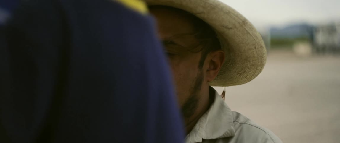Hispanic man wearing a hat holds an orange and white device while interacting with two children