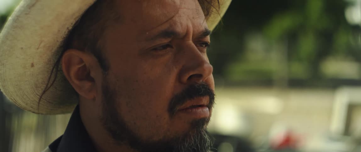 Man wearing a brimmed hat and a beard looks contemplative