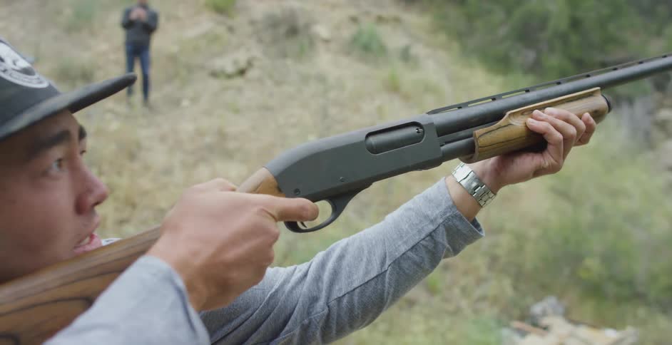 A man raises shotgun to aim at an object moving through the sky and fires before lowering the gun and exclaiming disappointment