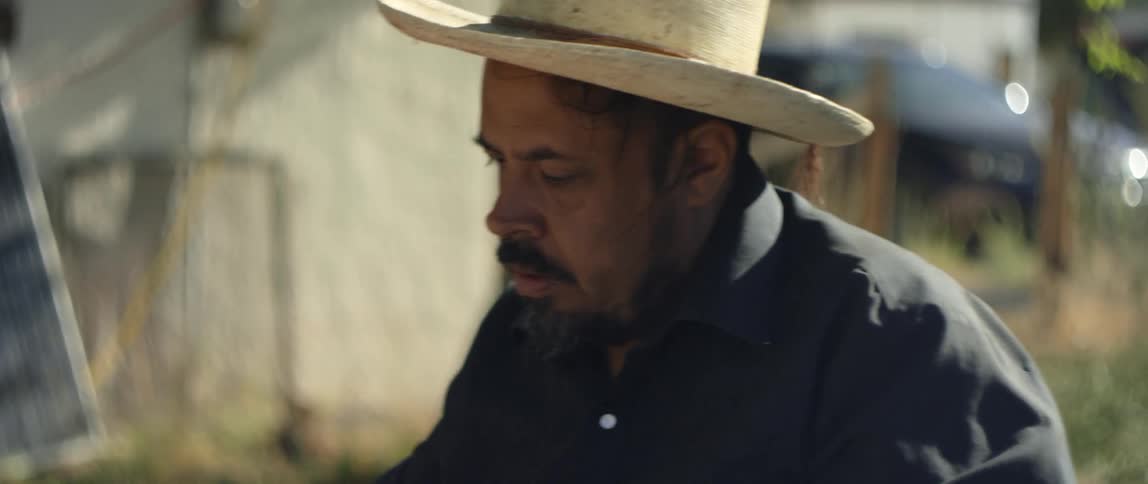 A man with a hat and a shirt holding a pencil and an envelope