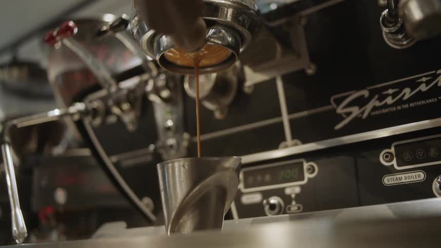 Hot beverage streams from a machine into a silver container