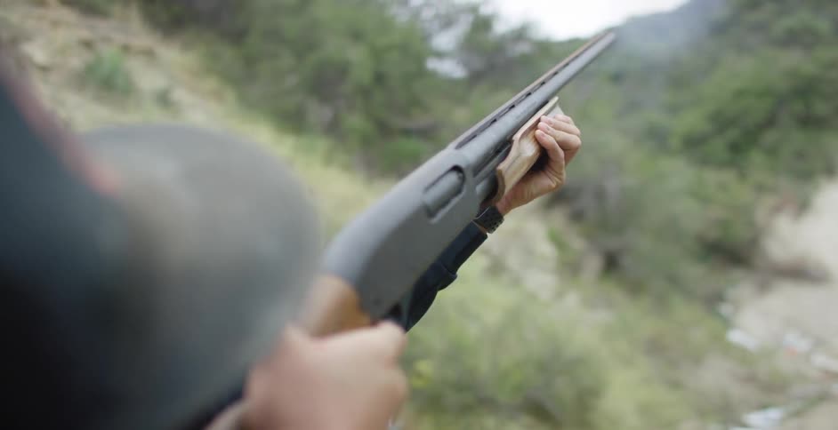 Man wearing ear plugs takes shot toward sky over slope while chewing gum