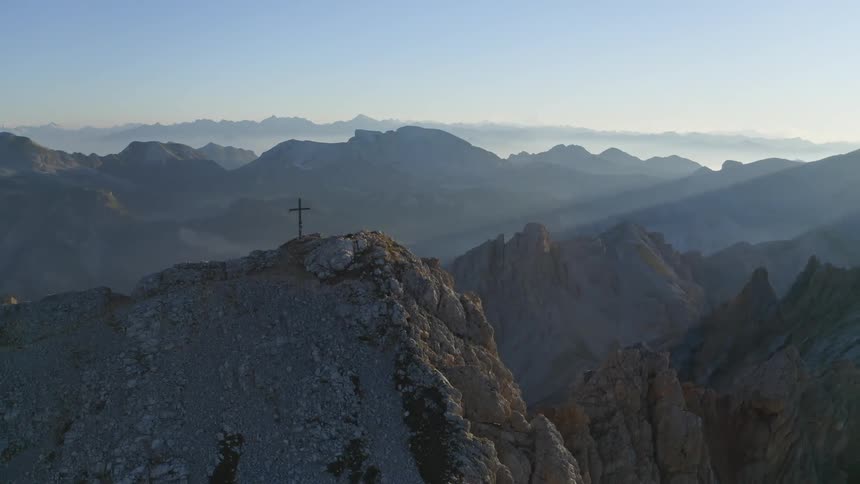Aerial view of cross on top of mountain at sunrise