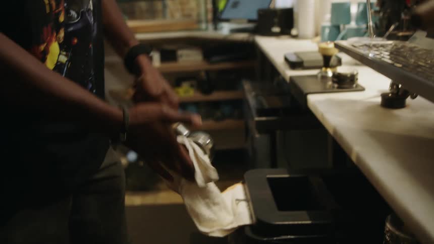 An employee at a coffee shop cleaning the coffee machine